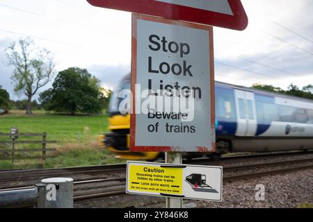 Northern Trains train passing Stop Look Listen sign at pedistrian crossing, Burley in Wharfedale, Ilkley, Leeds, West Yorkshire Stock Photo