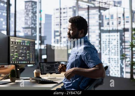 Programmer in pain, suffering muscle sprain while developing machine learning APIs solving complex problems. Man feeling backache from sitting on desk chair while training predictive models Stock Photo