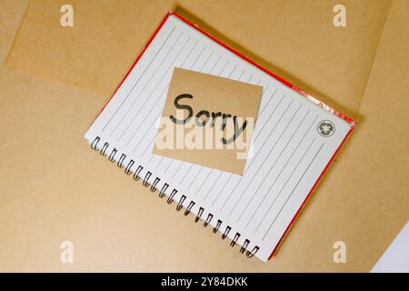 Forgiveness phrase written on recycled cardboard with a background of a lined notebook and sticky notes Stock Photo