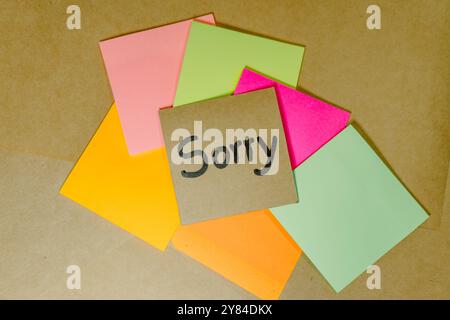 Forgiveness phrase written on recycled cardboard with a background of a lined notebook and sticky notes Stock Photo
