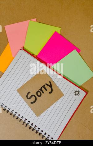 Forgiveness phrase written on recycled cardboard with a background of a lined notebook and sticky notes Stock Photo