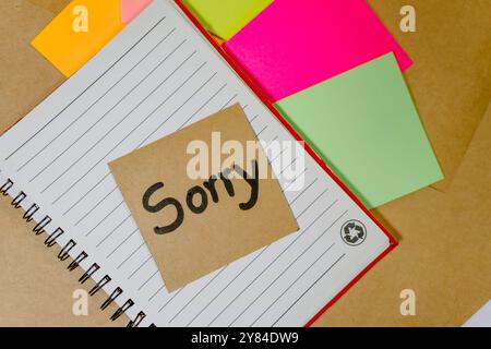 Forgiveness phrase written on recycled cardboard with a background of a lined notebook and sticky notes Stock Photo