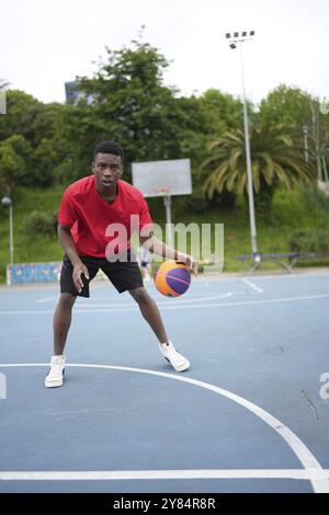 Full length vertical photo of an african american basketball player dribbling alone in an outdoor court Stock Photo