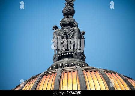 Palacio de Bellas Artes Dome Statues Mexico City | MEXICO CITY, Mexico — A close view of the repoussé-bronze crown atop the Palacio de Bellas Artes dome shows two of its four winged female figures, allegories of the dramatic arts, joined hand in hand beneath the Aztec eagle. Hungarian sculptor Géza Maróti designed the group, which was fabricated in Budapest and set on an elliptical white-marble base above the golden ceramic-tiled dome. Stock Photo