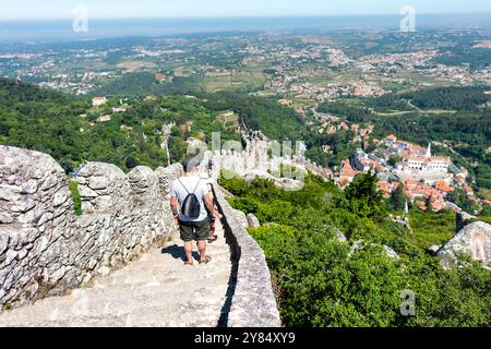 SINTRA, Portugal — A sweeping panoramic view from atop the ramparts of the Moorish Castle (Castelo dos Mouros) in Sintra. The medieval fortress, perched high in the Sintra Mountains, offers breathtaking vistas of the surrounding landscape, including glimpses of other historic landmarks and the distant Atlantic Ocean. Stock Photo