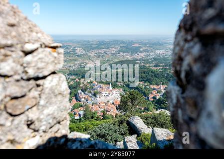 SINTRA, Portugal — A sweeping panoramic view from atop the ramparts of the Moorish Castle (Castelo dos Mouros) in Sintra. The medieval fortress, perched high in the Sintra Mountains, offers breathtaking vistas of the surrounding landscape, including glimpses of other historic landmarks and the distant Atlantic Ocean. Stock Photo