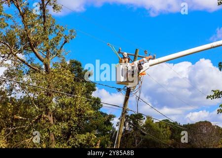 Utility tower truck is being used by emergency service linemen to perform repairs to power electrical lines damaged by storm hurricane Stock Photo