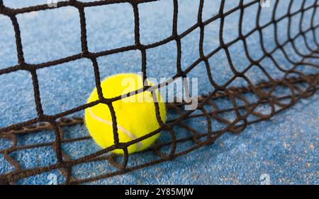 Ball in the shade of the net of a blue paddle tennis court. Stock Photo