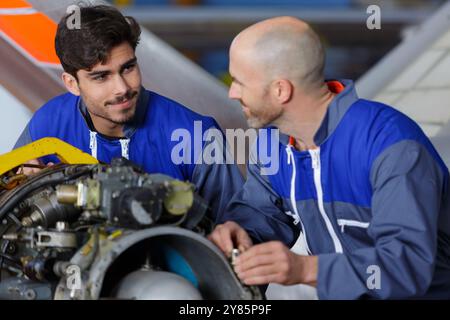 two engineers talking while working in a hangar Stock Photo