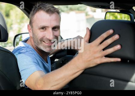 male car driver looking into the back of the car Stock Photo