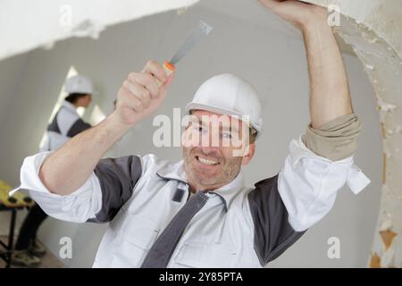 smiling builder in hardhats with tools indoors Stock Photo