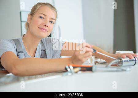 cheerful female plumber installing new tap Stock Photo
