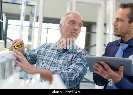 worker using tape-measure in plastic window and door manufacturing factory Stock Photo