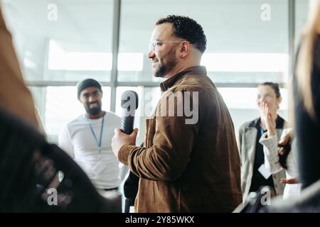 A confident business owner leads a team training session, fostering leadership and teamwork in a modern office setting with an engaging atmosphere. Stock Photo