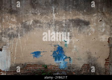 Front view of an old, dirty, damaged and plastered wall. Plaster is partly peeled off revealing old bricks. Full frame textured background. Stock Photo