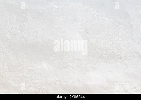 Front view of a clean and blank plastered wall painted in white on sunny day. Abstract high resolution full frame textured background with copy space. Stock Photo