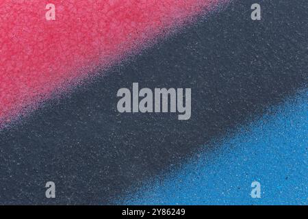 Macro close-up of a wall spray painted in pink, gray and blue. Abstract full frame textured splattered graffiti background with copy space. Stock Photo