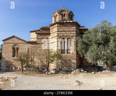 Ancient Byzantine-style stone church with domed roof and cross on top, surrounded by trees and path in Athens, Greece. Outdoor architectural photograp Stock Photo