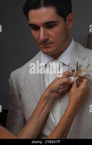 Groom receiving the flower pin or boutonniere on his lapel with a serious expression, Spain Stock Photo