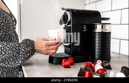 Girl hand with capsule coffee machine at home. Woman making espresso in caffeine beverage maker Stock Photo