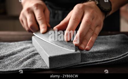 Man sharpening a knife with whetstone, closeup view Stock Photo