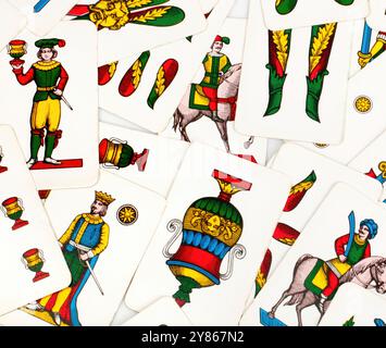 Colorful antique italian playing cards are scattered showing knights, cups, swords, and batons Stock Photo