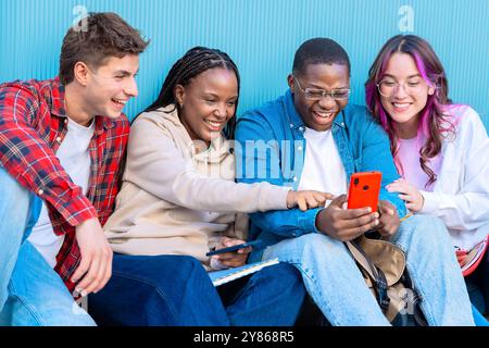 Diverse young people sitting outdoors using smartphones Stock Photo