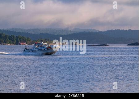 A taxi boat speeds across the water among islands, islets and skerries in the Kragerø archipelago in Telemark county, Norway. Stock Photo