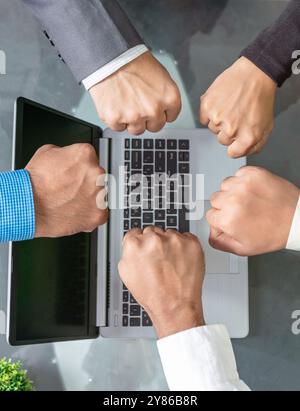 A close-up, top view of a diverse group of multiethnic businesspeople engaging in a fist bump during a team-building activity in a corporate meeting r Stock Photo