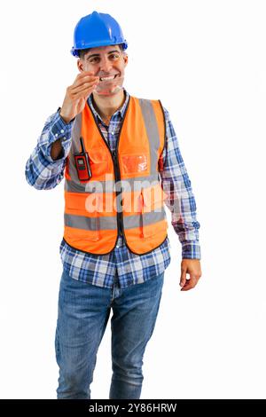 vertical construction worker dressed in an orange safety vest and hard hat is putting on his safety glasses at a construction site. The image emphasiz Stock Photo