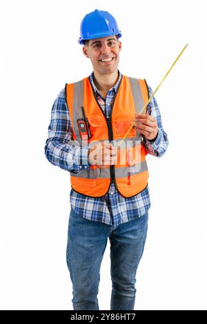 vertical cheerful construction worker dressed in an orange safety vest and hard hat is smiling while holding a measuring tape, white background Stock Photo