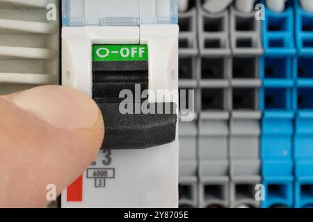 Hand switching off electrical circuit breaker in panel Stock Photo