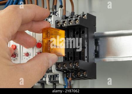 Inserting relay into electrical control panel Stock Photo