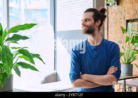 Portrait of young confident handsome man with crossed arms, profile view Stock Photo