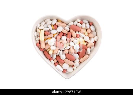 Plate in shape of heart with heap of medicine pills or dietary supplements isolated on white background Stock Photo