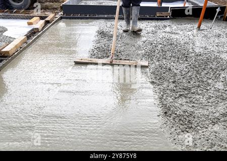 Curated visual reference: Fresh Look at Construction Worker Leveling Wet Cement Into Wood Framing Stock Photo