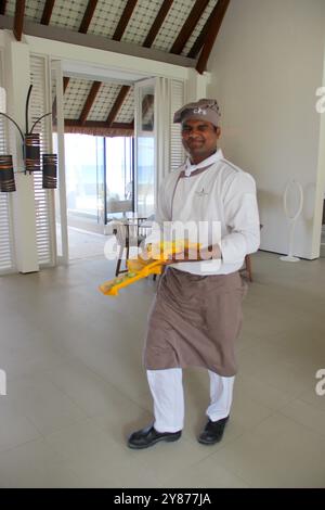 Maldives - March 7, 2014: A chef with Maldivian ethnicity walking in a restaurant with a yellow tea towel and making a funny face Stock Photo