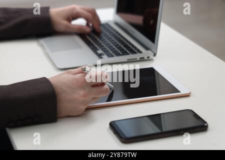 Businessman using different devices at white table indoors, closeup. Modern technology Stock Photo