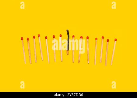 Wooden matches sticks, one burned on a yellow background with copy space Stock Photo