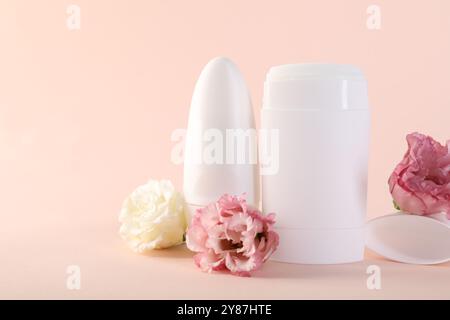 Different deodorants and beautiful eustoma flowers on beige background Stock Photo