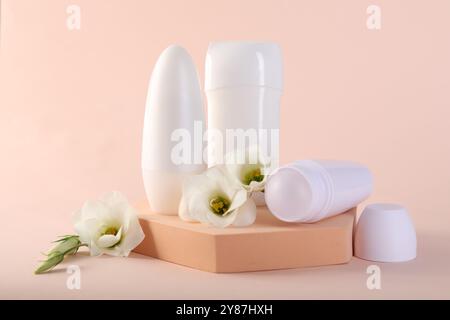 Different deodorants and beautiful eustoma flowers on beige background Stock Photo