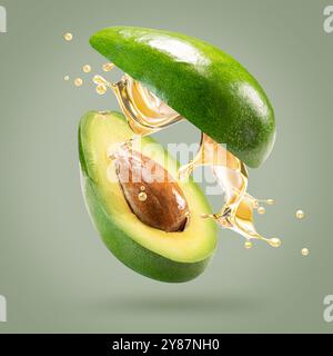 avocado with oil splash on a light green background. Stock Photo