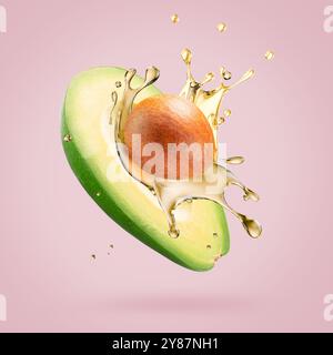 avocado with oil splash on a light pink background. Stock Photo