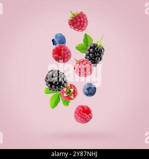 falling raspberries, blackberries and blueberries on a light pink background. Stock Photo