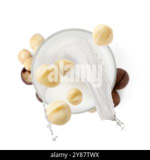 Macadamia nuts falling into glass of milk on white background, top view Stock Photo