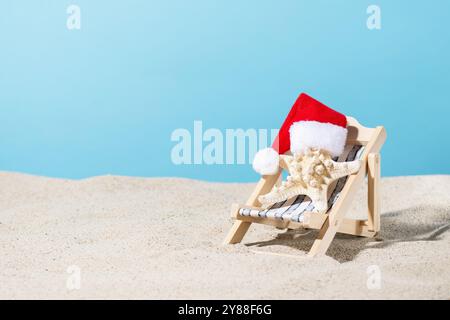 Starfish in Santa hat on sand beach over blue background. Christmas tropical vacation creative idea. Stock Photo