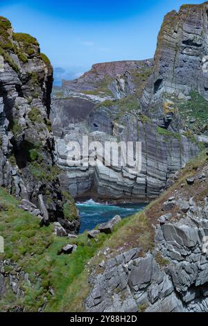 Waves Crashing Against the Rocky Cliffs of Mizen Head viewed from the footbridge framed by rock formation Stock Photo