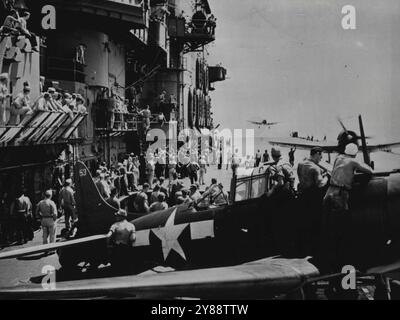 U.S. Navy Task Force Blasts Rabaul -- The deck of the U.S. Navy's aircraft carrier Saratoga presents a busy scene as a Dauntless dive bomber comes in for a landing after dropping its bombs on Rabaul, major Japanese base on New Britain Island in the South Pacific, during a raid by an American naval task force on Nov. 5, 1943. In the foreground, crew members check over a plane that has recently landed, while just behind it another plane, its propeller still spinning, taxis to a stop. The raid, in which 24 Japanese planes were shot down, severely crippled the enemy base, marking another successfu Stock Photo