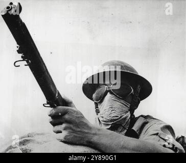 Desert Fighter -- A British soldier, wearing goggles and a handkerchief to protect himself in desert sand storms, rests his rifle on a sandbag at an outpost in Africa. June 17, 1941. (Photo by Associated Press Photo). Stock Photo