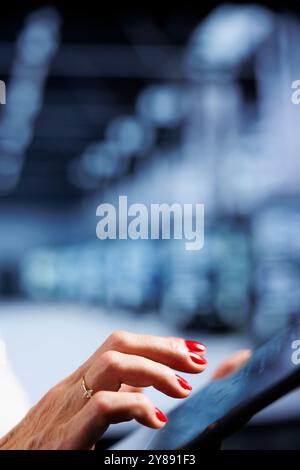 Computer scientist using tablet, ensuring valuable data remains shielded from potential risks, safeguarding server mainframes against unauthorized access and vulnerabilities, close up Stock Photo